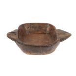 A large heavy wooden Indian bowl, of stylised form, flanked by wedge shaped handles, 60cm overall