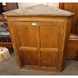 An 18th Century oak hanging corner cupboard, interior shelves enclosed by a quarter panelled door,