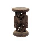 An ethnic carved hardwood stool, with triple mask decoration, 46cm high, 30cm dia.; a carved ebony