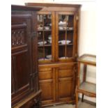 A Georgian design oak corner cabinet, the upper shaped shelves enclosed by glazed panel doors,