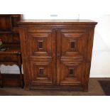 An Antique oak storage cupboard, enclosed by a pair of quarter panel moulded doors, raised on square