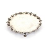 A silver salver, by Elkington & Co., having pie crust border, raised on three hoof feet,