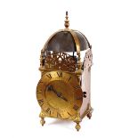 An 18th Century brass lantern clock, the bell surmounted by an urn finial above pierced sides, Roman