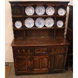 An Antique oak dresser, having shelved and boarded plate rack, three drawers and cupboards below,