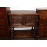 An Antique carved oak side cupboard, enclosed by a pair of foliate panelled doors, raised on