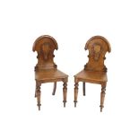 A pair of Victorian oak hall chairs, having shield shaped backs, solid seats raised on turned