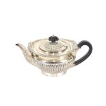 A late Victorian silver teapot, by the Goldsmiths and Silversmiths Co., having half fluted body