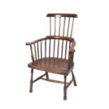 An 18th Century rustic elm seated comb back elbow chair, the shaped seat raised on baluster turned