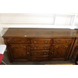 An 18th Century style oak dresser base, fitted six drawers, interior shelves enclosed by a pair of