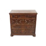 An 18th Century oak chest, fitted four long drawers with geometric moulded fronts, brass acorn