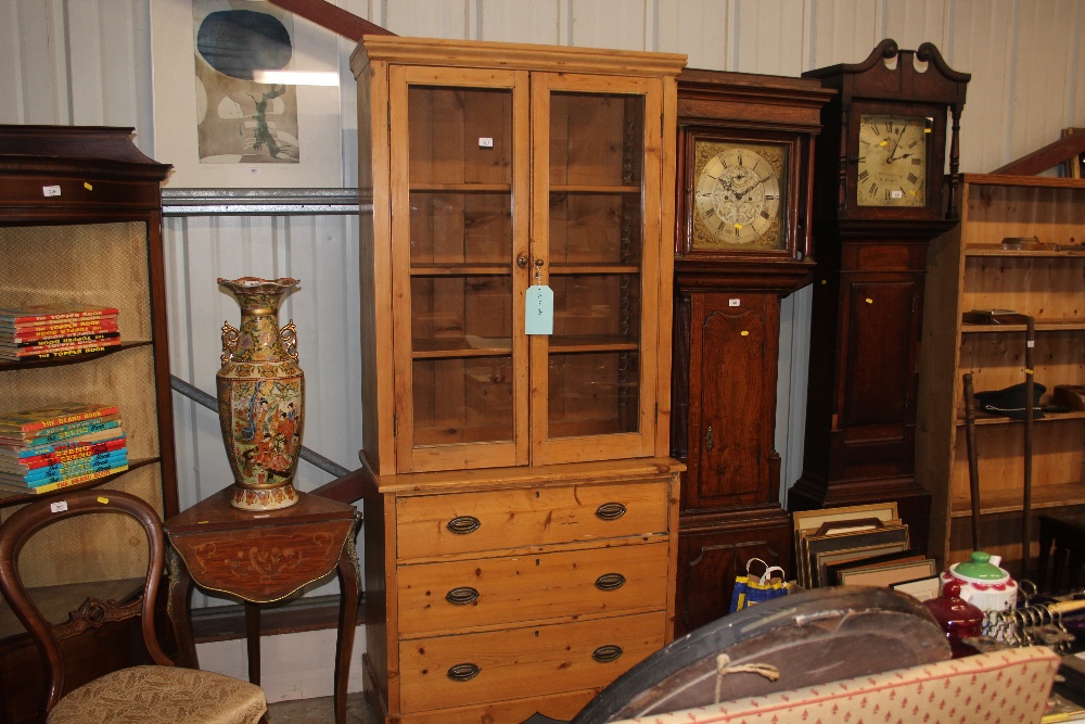 A stripped pine and glazed bookcase raised on thre