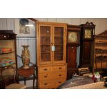 A stripped pine and glazed bookcase raised on thre