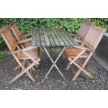 A teak folding table with a set of four folding ch