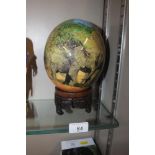 An Ostrich egg decorated with elephants mounted on