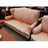 A large early 20th Century three seater Country House wing back settee, upholstered in floral