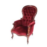 A Victorian mahogany framed spoon back armchair, upholstered in red buttoned dralon, scroll arms