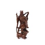 A Chinese hardwood figure, depicting a man fighting with a wild cat, carrying club and libation cup,