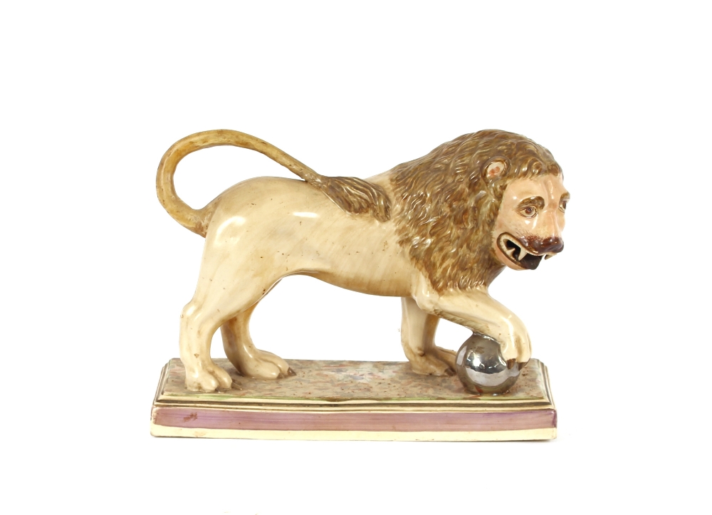 A 19th Century Staffordshire lion figure, right paw resting on a ball, 34cm long