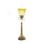 A Victorian brass column oil lamp, having leaf decoration, clear glass reservoir, raised on a marble