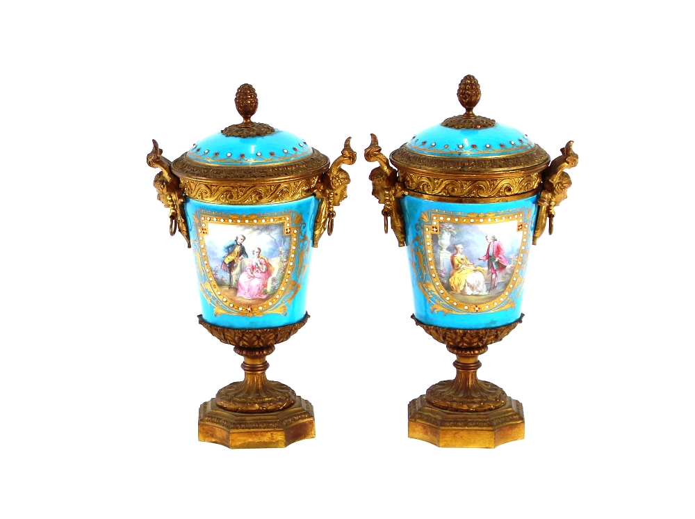 A pair of 19th Century Sevres style gilt metal mounted urns and covers, surmounted by foliate and