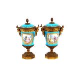 A pair of 19th Century Sevres style gilt metal mounted urns and covers, surmounted by foliate and