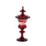 A Bohemian ruby glass goblet and cover, decorated with stags in a forest scene, (chip to base and