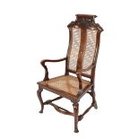 An 18th Century continental walnut elbow chair, having cane seat and back-panels, scrolled and