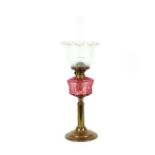 A Victorian brass oil lamp, with ruby glass reservoir and floral shade, 70cm
