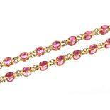 A yellow metal and pink stone long necklace