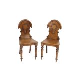 A pair of Victorian oak hall chairs, shield shaped back above solid seats, raised on turned tapering