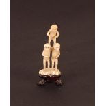 A small carved ivory Monkey group, on carved wooden stand, 10cm high