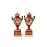 A pair of Vienna porcelain urns and covers, decorated with cherubs on a pink and red ground