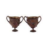 A pair of classical bronze urns, decorated satyr and cherubs, flanked by foliate handles, 15cm high