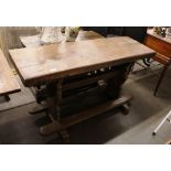 An elm refectory type table, of narrow proportions, raised on shaped ends pegged, united by
