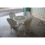 An ornate garden table and four matching chairs