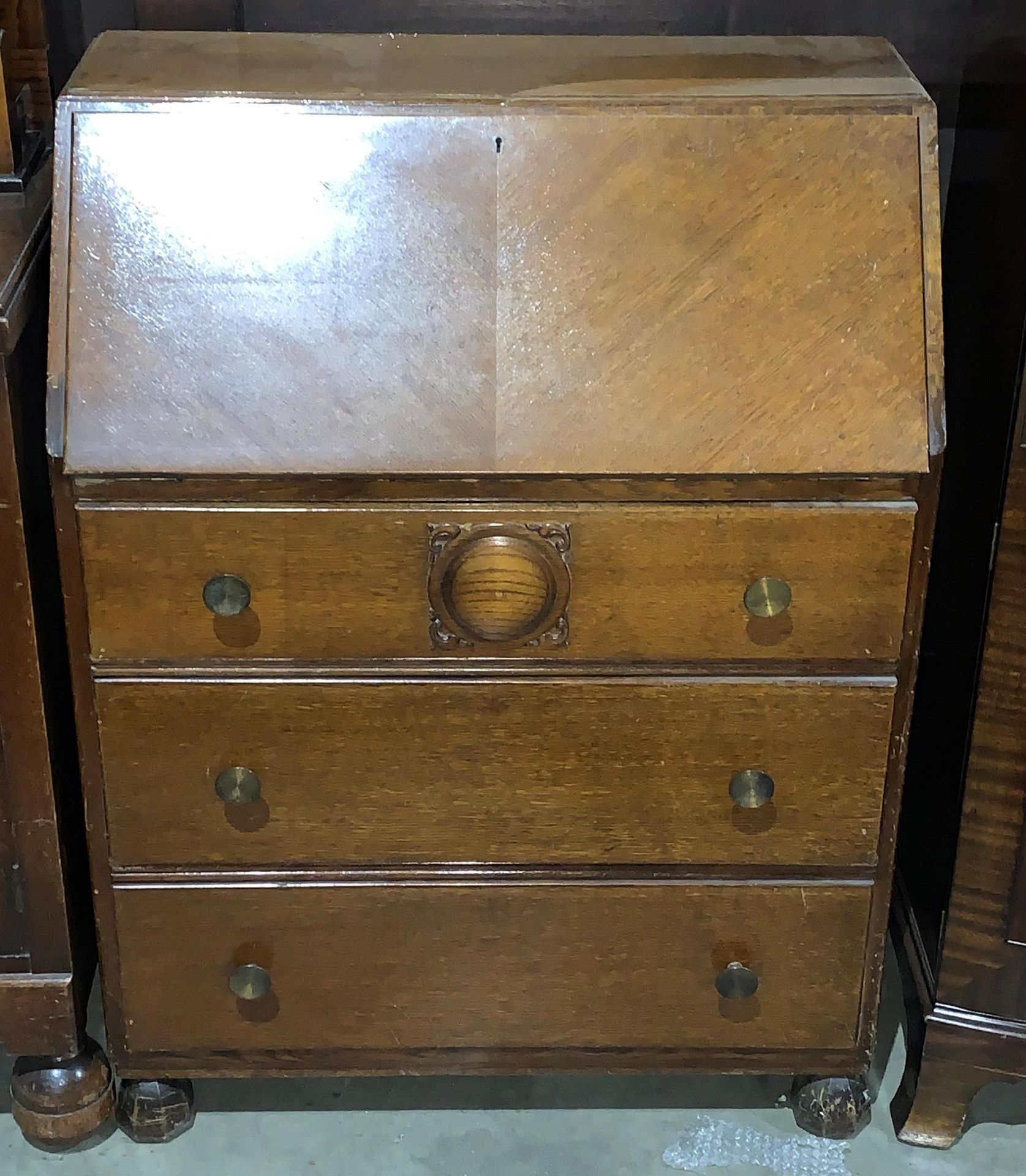 An oak bureau with fall flap over three drawers,