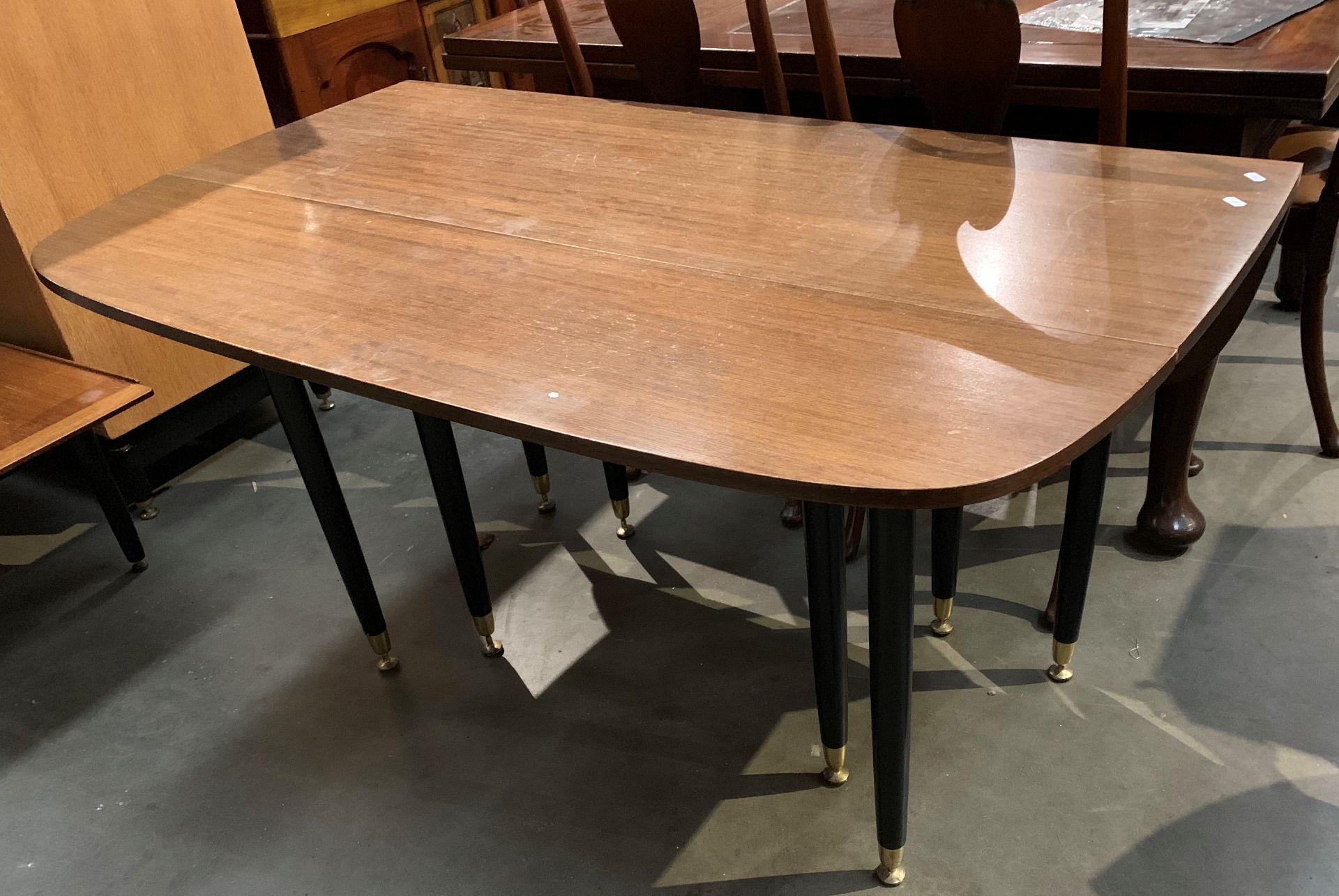 A mahogany finish drop leaf dining table on panted black wood legs,