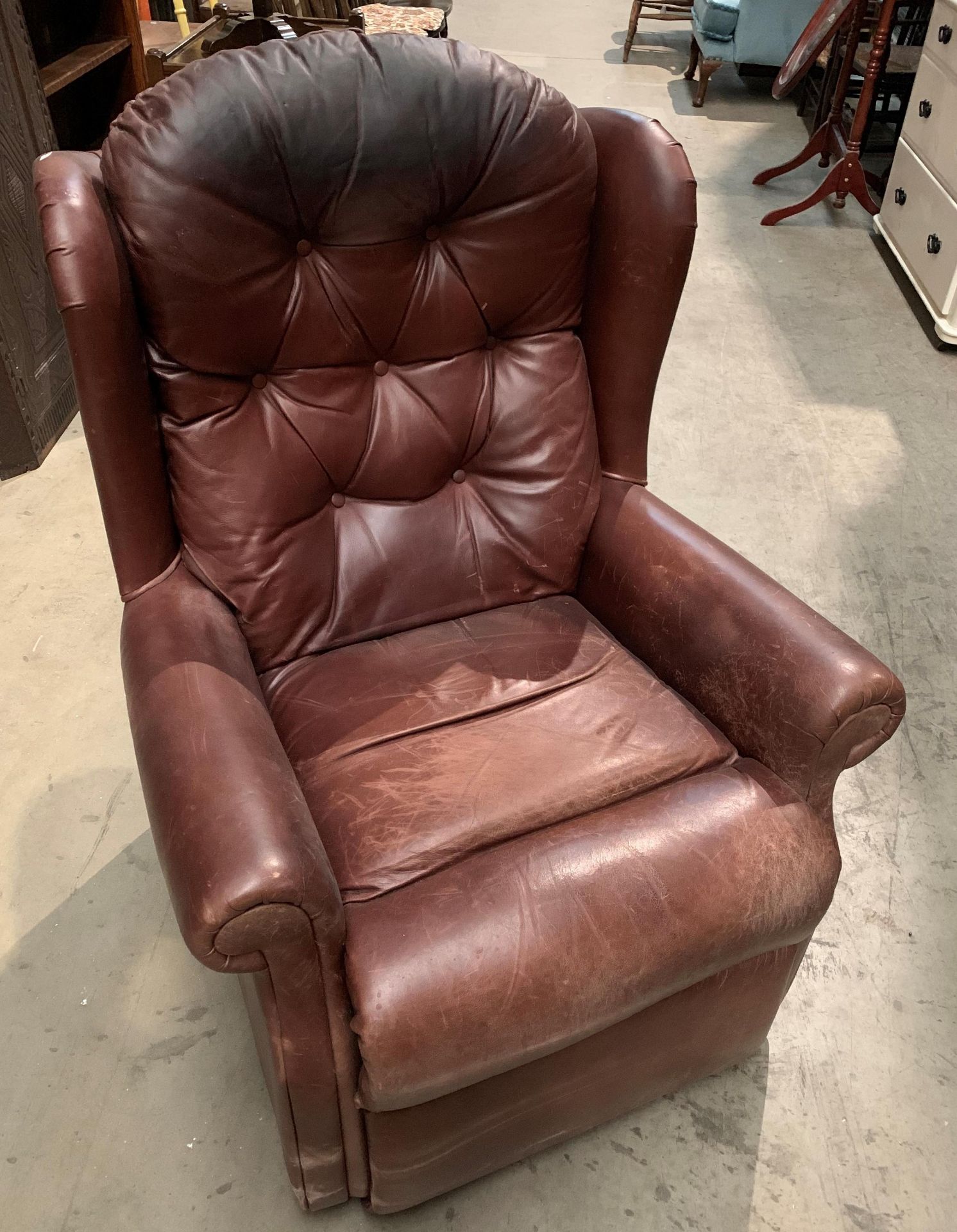 A brown distressed leather deep buttoned back armchair