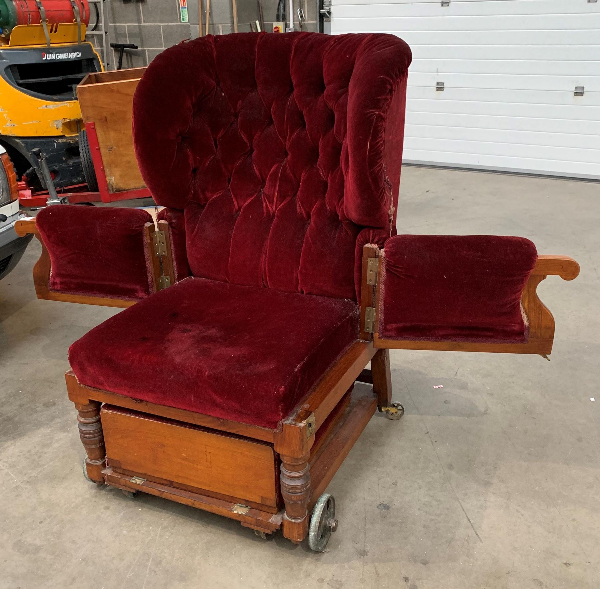 A Victorian invalid chair recovered in red velvet raised on brass wheels and labelled Leveson and