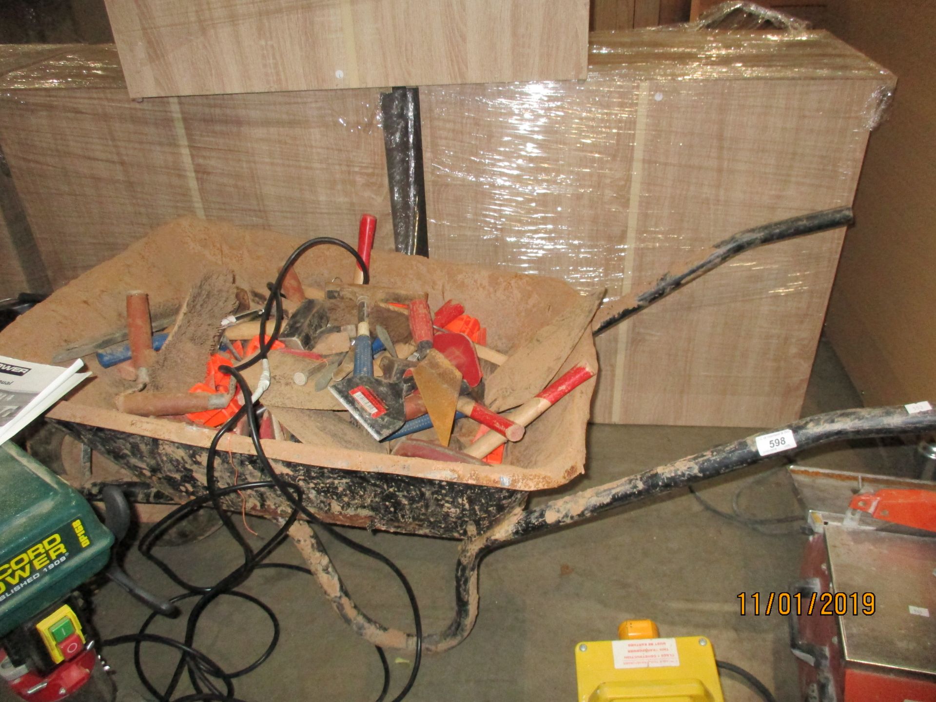 A black metal wheel barrow and contents - plasterers' trowels, brush heads, mallets etc.
