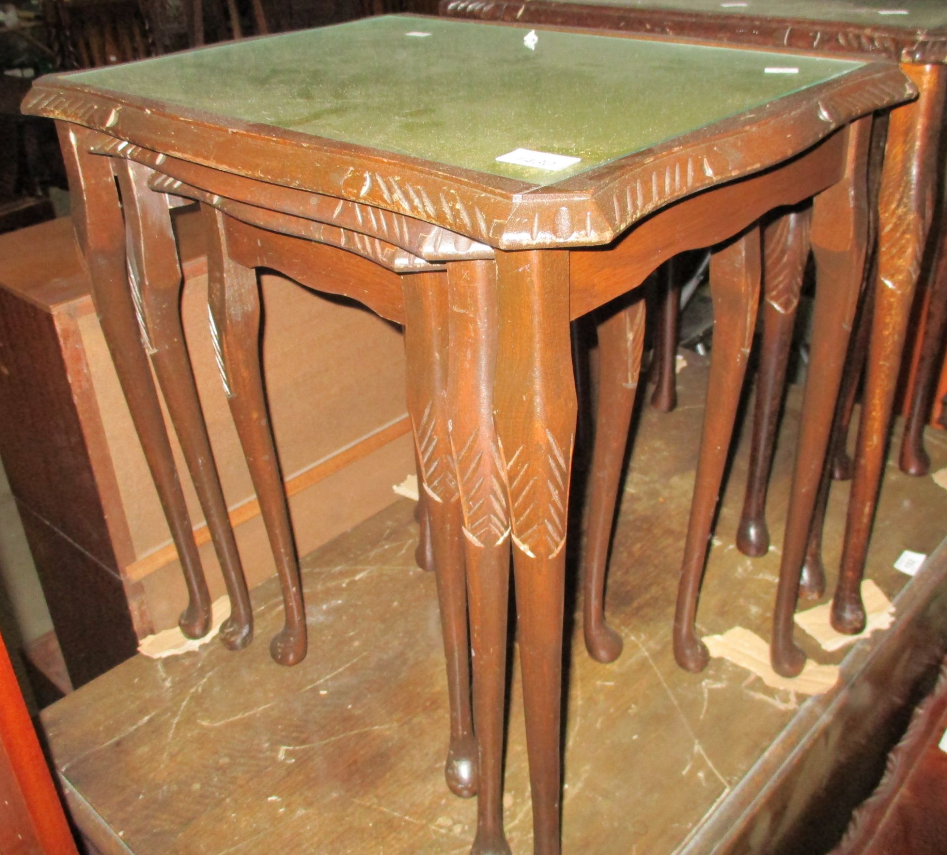 A nest of 3 dark oak finish coffee tables with tooled green leatherette tops and glass inserts