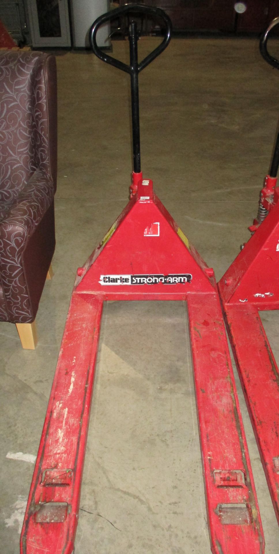 A Clarke Strong Arm red metal pallet truck