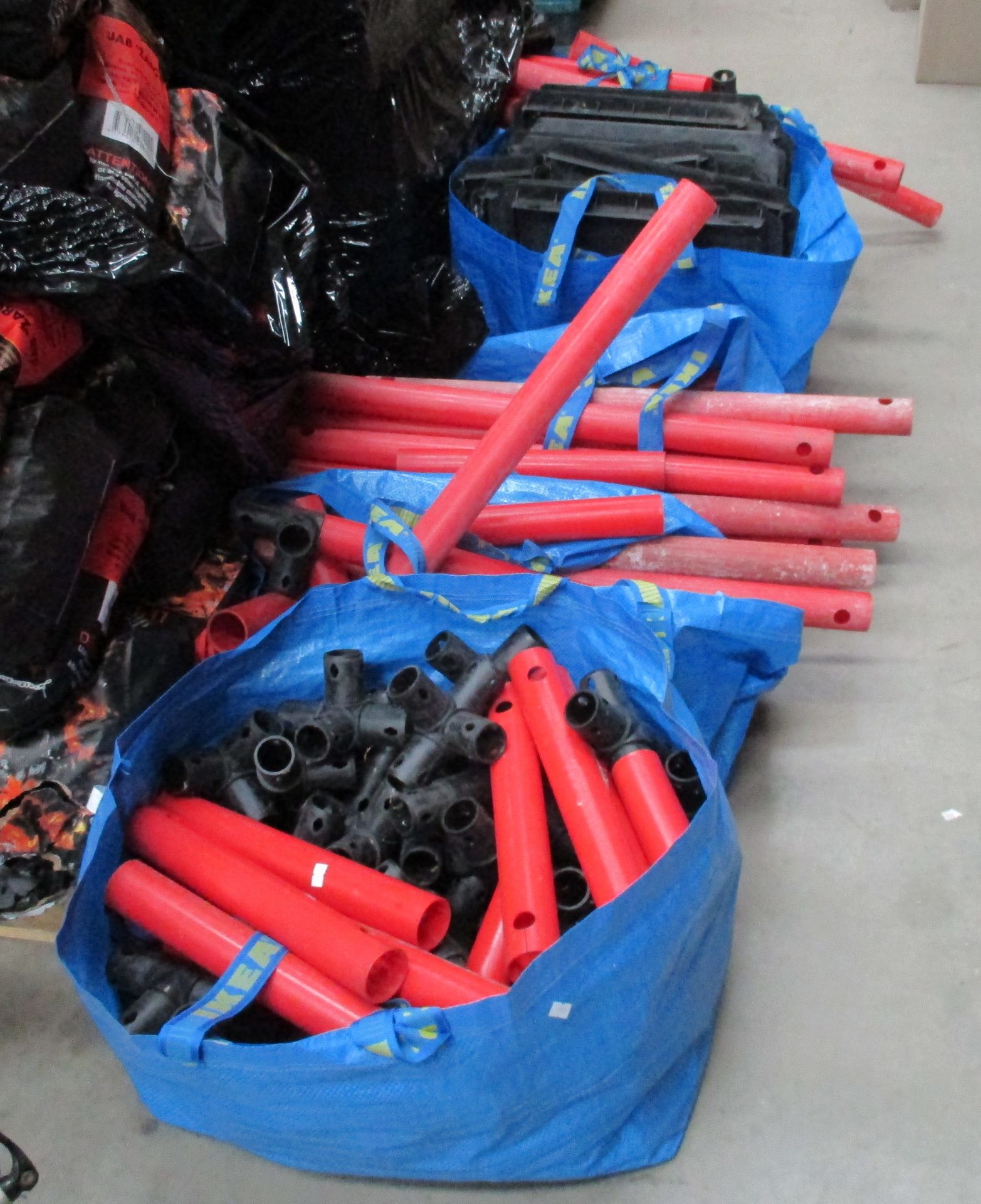 Contents to 4 blue bags - red plastic tubular and black rubber component parts for an exhibition