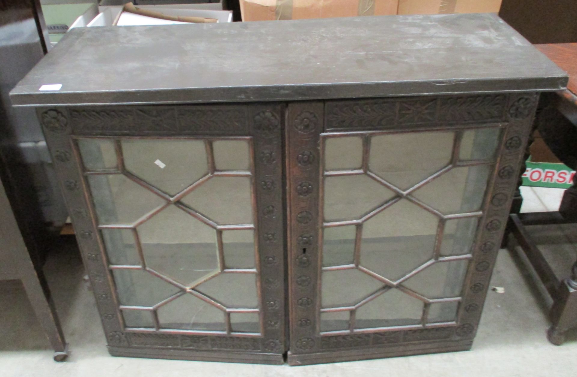 An oak cabinet with glazed top section (one panel cracked) with Yorkshire Rose carving to door