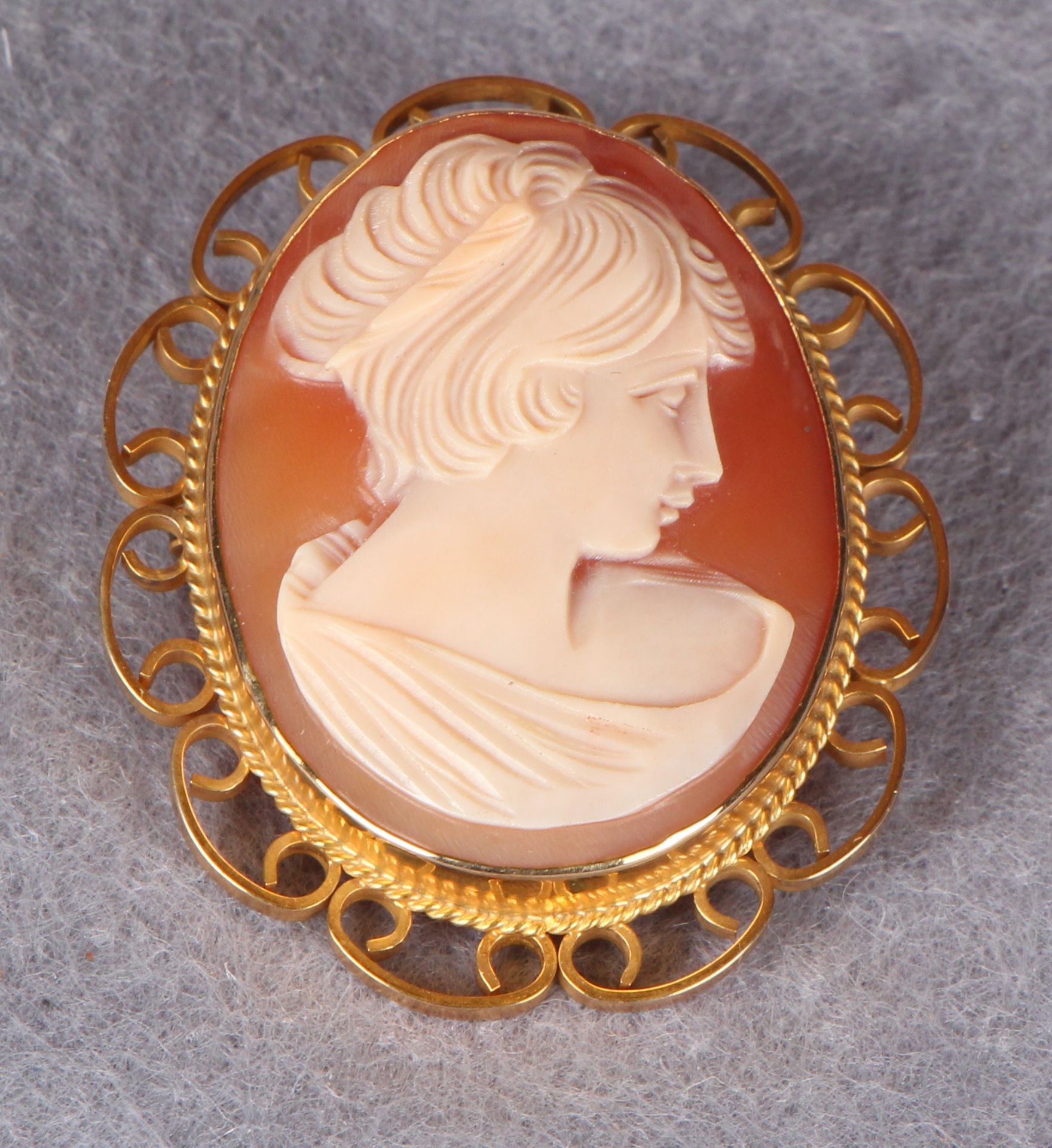 An oval shell cameo, carved with a profile head of a young woman, gold frame, stamped 9.