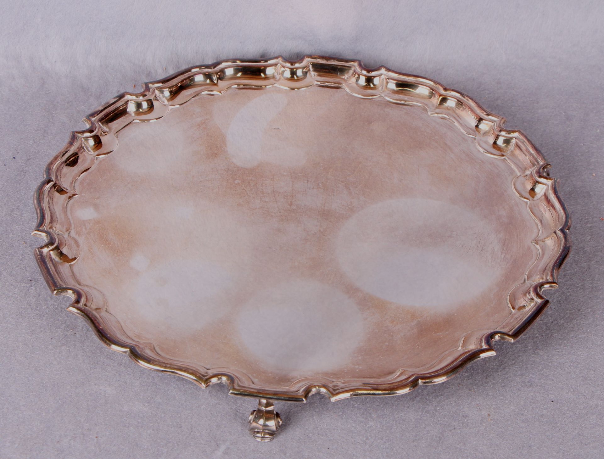 A presentation salver of shaped circular form, piecrust border, three scroll feet,