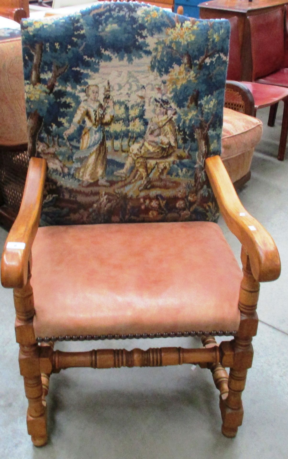 An oak framed armchair with tapestry back and light brown hide seat