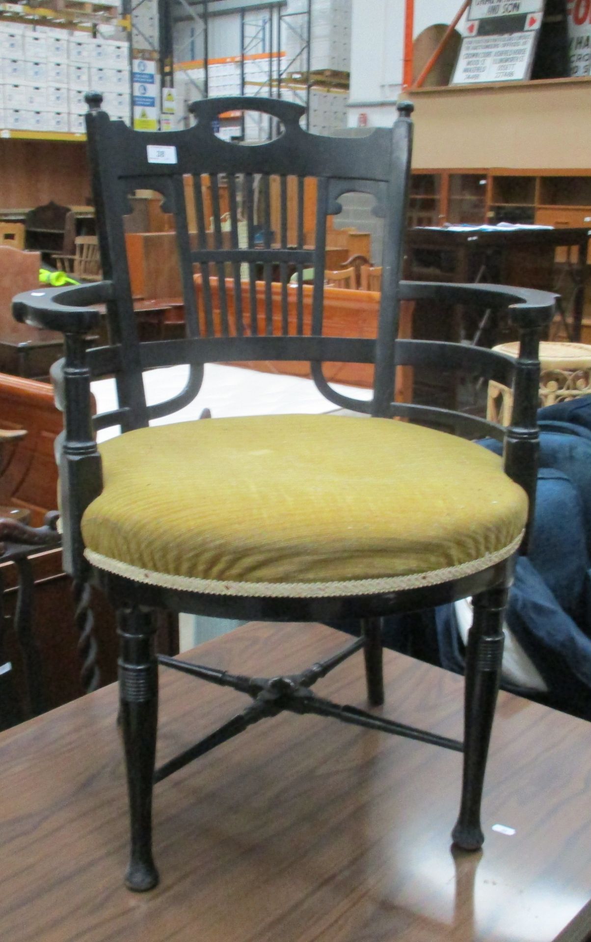 An Edwardian ebonised open elbow chair with upholstered seat