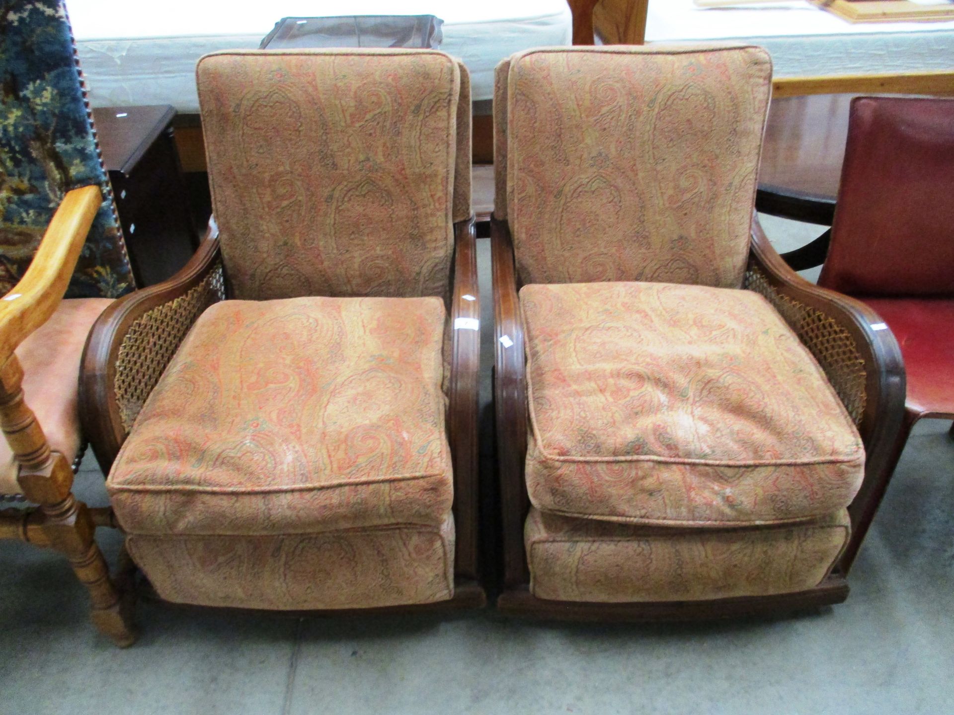 A pair of mahogany framed easy armchairs with woven sides and brown patterned upholstered seat