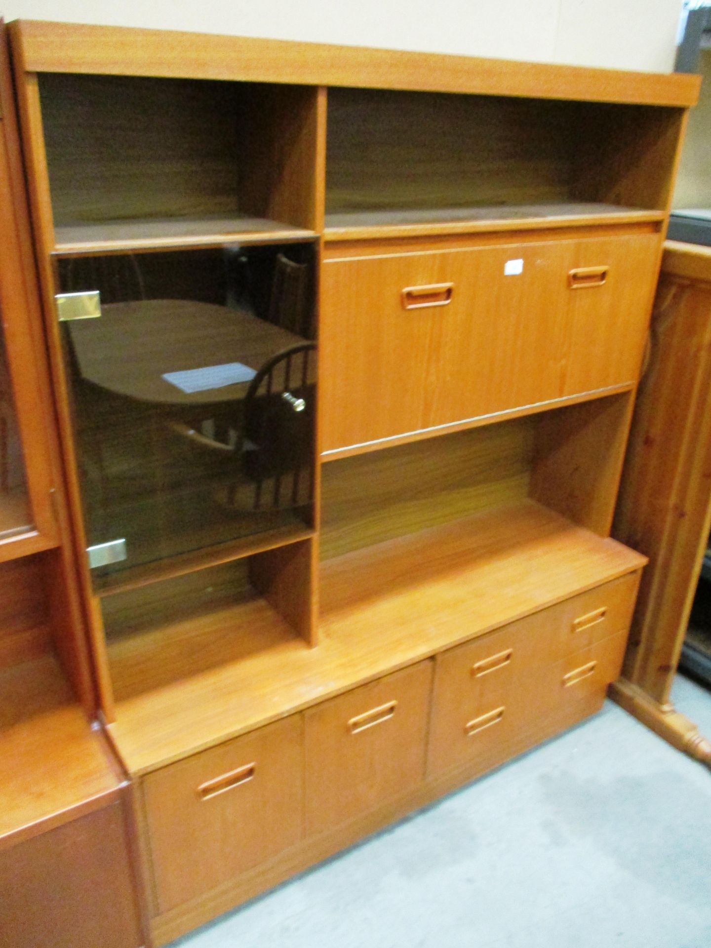 A teak wall unit with 3 upper doors (1 smoked glass glazed) over 2 drawers 2 door base 136 x 168cm